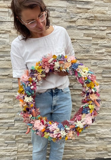 Frau hält bunten Trockenblumenkranz